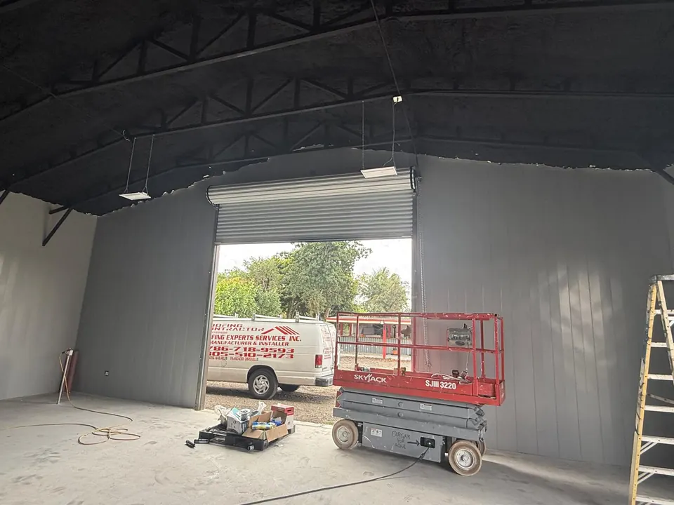 Hangar wall panel installation beside roll-up opening