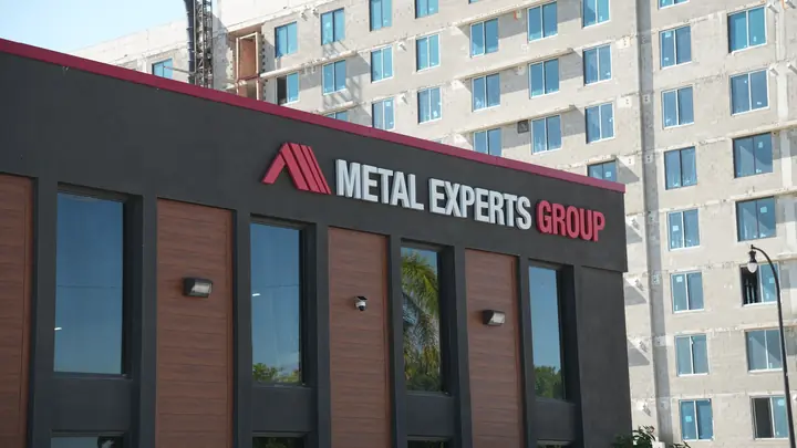 Brick-look metal panels with palm reflections in glass